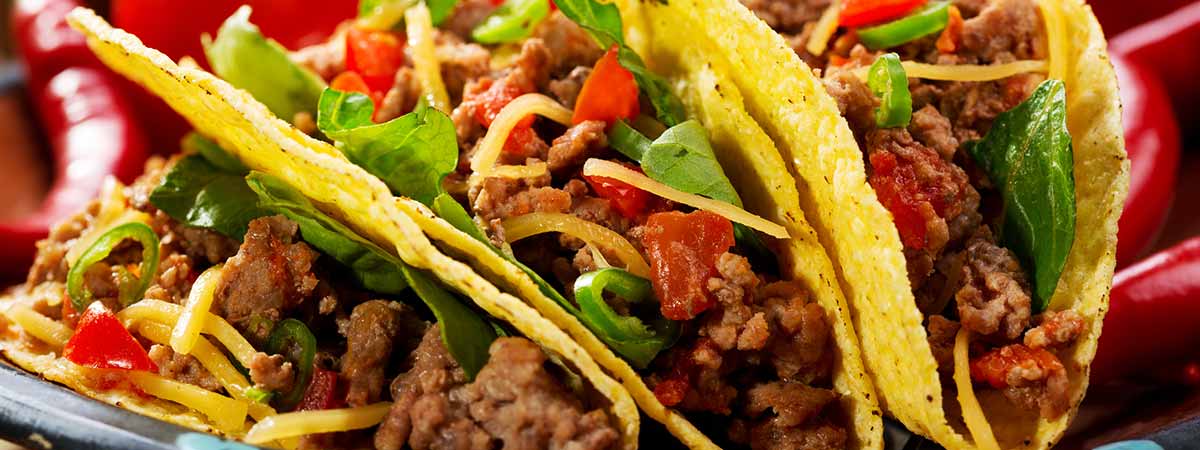 Three seasoned beef tacos with onion, cilantro, and lime